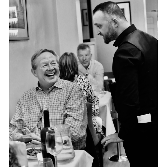 A guest sharing a laugh with a waiter at L'unico Chelmsford